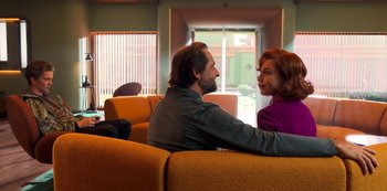 Movie still from “Big Bug” (2022), directed by Jean-Pierre Jeunet – A man and a woman are sitting on a couch together; Medium shot, Over the shoulder angle