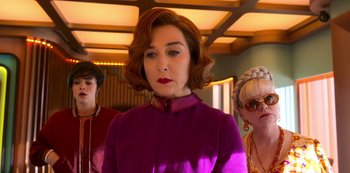 Movie still from “Big Bug” (2022), directed by Jean-Pierre Jeunet – A woman in a purple dress standing next to two other women; Medium shot, Low angle