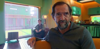 Movie still from “Big Bug” (2022), directed by Jean-Pierre Jeunet – A man sitting in front of another man in a chair; Medium shot, Over the shoulder angle