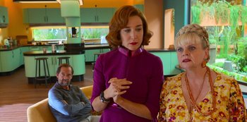 Movie still from “Big Bug” (2022), directed by Jean-Pierre Jeunet – A woman standing next to two other people in a room; Medium shot, Over the shoulder angle