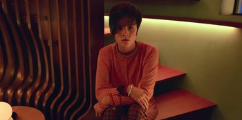 Movie still from “Big Bug” (2022), directed by Jean-Pierre Jeunet – A woman sitting on a step with her arms crossed; Medium shot, High angle