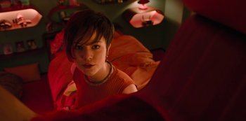 Movie still from “Big Bug” (2022), directed by Jean-Pierre Jeunet – A woman sitting on top of a bed looking at the camera; Medium shot, High angle