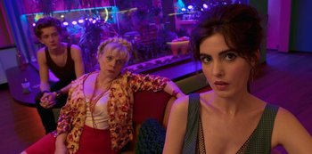 Movie still from “Big Bug” (2022), directed by Jean-Pierre Jeunet – Two women sitting on a red couch in a room; Medium shot, Low angle