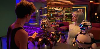 Movie still from “Big Bug” (2022), directed by Jean-Pierre Jeunet – Two people are sitting at a table in a room; Medium shot, Over the shoulder angle