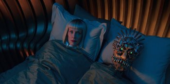Movie still from “Big Bug” (2022), directed by Jean-Pierre Jeunet – A woman laying in a bed next to a mask; Close Up shot, Overhead angle