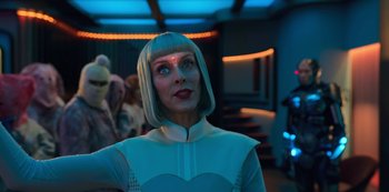 Movie still from “Big Bug” (2022), directed by Jean-Pierre Jeunet – A woman in a white outfit and a white wig looking to her left; Medium shot, Over the shoulder angle