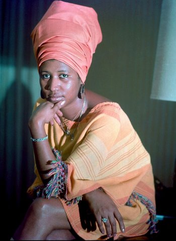 Movie still from “Da 5 Bloods” (2020), directed by Spike Lee – A woman with a head wrap sitting on a chair; Close Up shot, Low angle