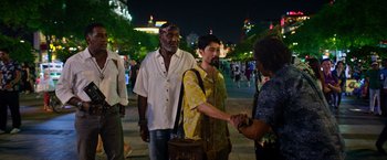 Movie still from “Da 5 Bloods” (2020), directed by Spike Lee – A group of people shaking hands on the sidewalk; Medium shot, Over the shoulder angle