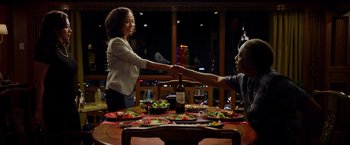 Two people shaking hands over a dinner table