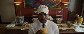 Movie still from “Da 5 Bloods” (2020), directed by Spike Lee – A man in a white shirt and tie holding a glass of orange juice; Close Up shot, Over the shoulder angle