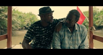 Movie still from “Da 5 Bloods” (2020), directed by Spike Lee – Two men sitting next to each other on the ground; Medium shot, Over the shoulder angle