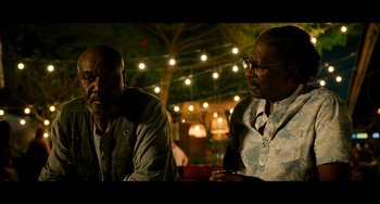 Movie still from “Da 5 Bloods” (2020), directed by Spike Lee – A couple of men sitting next to each other at a table; Medium shot, Over the shoulder angle