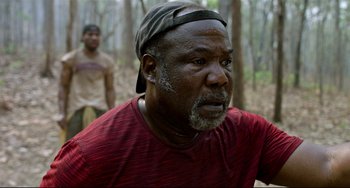 Movie still from “Da 5 Bloods” (2020), directed by Spike Lee – An older man in a red shirt is looking at the camera; Close Up shot, Low angle