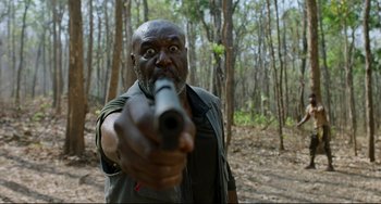 Movie still from “Da 5 Bloods” (2020), directed by Spike Lee – A man holding a gun in the middle of a forest; Medium shot, Low angle