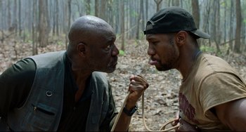 Movie still from “Da 5 Bloods” (2020), directed by Spike Lee – Two men in the woods one of which has his mouth open; Close Up shot, Over the shoulder angle
