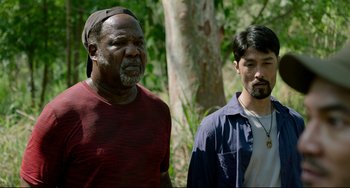 Movie still from “Da 5 Bloods” (2020), directed by Spike Lee – Two men standing next to each other near a tree; Medium shot, Over the shoulder angle