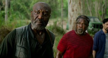 Movie still from “Da 5 Bloods” (2020), directed by Spike Lee – Two men standing next to each other near a tree; Medium shot, Over the shoulder angle