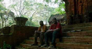 Movie still from “Da 5 Bloods” (2020), directed by Spike Lee – A couple of men sitting next to each other on some steps; Medium shot, High angle