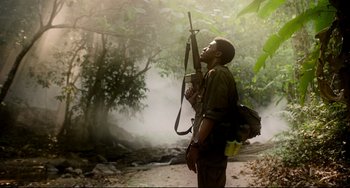 Movie still from “Da 5 Bloods” (2020), directed by Spike Lee – A man holding a gun while standing in the woods; Medium shot, Low angle