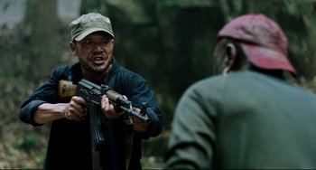 Movie still from “Da 5 Bloods” (2020), directed by Spike Lee – A man holding a gun in his hand and another man holding a gun in his other hand; Medium shot, Over the shoulder angle
