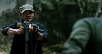 Movie still from “Da 5 Bloods” (2020), directed by Spike Lee – A man holding a gun while standing in the woods; Medium shot, Low angle