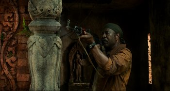 Movie still from “Da 5 Bloods” (2020), directed by Spike Lee – A man holding a gun while standing next to a statue; Medium shot, Low angle