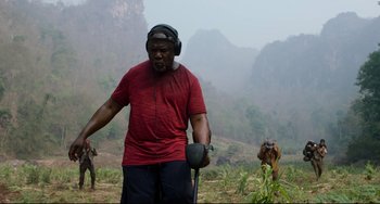 Movie still from “Da 5 Bloods” (2020), directed by Spike Lee – A man in a red t - shirt is listening to headphones; Medium shot, Low angle