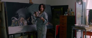 Movie still from “Bird Box” (2018), directed by Susanne Bier – A woman holding a paint brush in front of an easel; Medium shot, Over the shoulder angle
