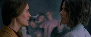 Movie still from “Bird Box” (2018), directed by Susanne Bier – Two women are facing each other in front of a group of people; Close Up shot, Over the shoulder angle