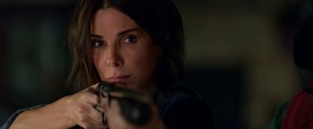 Movie still from “Bird Box” (2018), directed by Susanne Bier – A beautiful woman holding a gun in her hand; Close Up shot, Over the shoulder angle