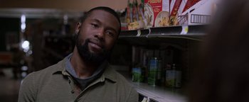 Movie still from “Bird Box” (2018), directed by Susanne Bier – A man sitting in front of a shelf of food; Close Up shot, Over the shoulder angle