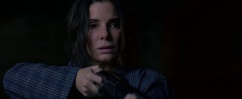 Movie still from “Bird Box” (2018), directed by Susanne Bier – A woman holding a gun in a dark room; Close Up shot, High angle