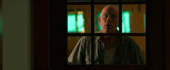 Movie still from “Bird Box” (2018), directed by Susanne Bier – An older man looking out of a window at night; Medium shot, Low angle