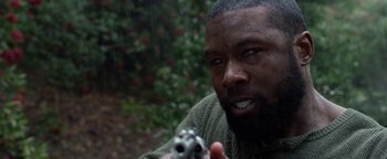 Movie still from “Bird Box” (2018), directed by Susanne Bier – A man holding a gun pointed at the camera; Close Up shot, Over the shoulder angle