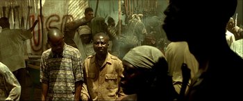 Movie still from “Black Hawk Down” (2001), directed by Ridley Scott – A group of men standing around in front of a group of people; Medium shot, High angle