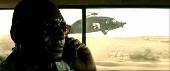 Movie still from “Black Hawk Down” (2001), directed by Ridley Scott – A man with glasses is looking out of a window at a helicopter; Close Up shot, Over the shoulder angle