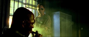 Movie still from “Black Hawk Down” (2001), directed by Ridley Scott – A man standing next to another man smoking a cigarette; Medium shot, Low angle