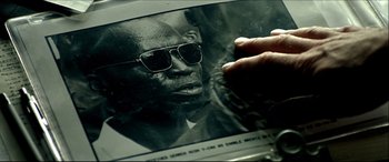 Movie still from “Black Hawk Down” (2001), directed by Ridley Scott – An old photo of a man wearing sunglasses; Extreme Close Up shot, Over the shoulder angle