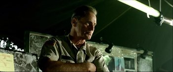 Movie still from “Black Hawk Down” (2001), directed by Ridley Scott – An older man in a military uniform with his arms crossed; Close Up shot, Low angle
