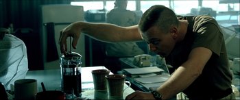 Movie still from “Black Hawk Down” (2001), directed by Ridley Scott – A man sitting at a table with two cups of coffee; Medium shot, Over the shoulder angle
