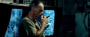 Movie still from “Black Hawk Down” (2001), directed by Ridley Scott – A man smoking a cigar in front of a television; Close Up shot, Low angle