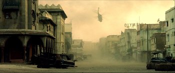 Movie still from “Black Hawk Down” (2001), directed by Ridley Scott – A helicopter is flying over a dusty city; Extreme Wide shot, Low angle
