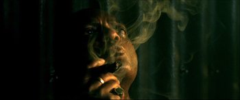 Movie still from “Black Hawk Down” (2001), directed by Ridley Scott – A man smoking a cigarette in a dark room; Extreme Close Up shot, Low angle