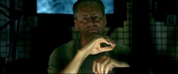 Movie still from “Black Hawk Down” (2001), directed by Ridley Scott – A man sitting in front of a tv with his fingers crossed; Close Up shot, Low angle
