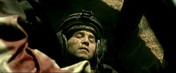 Movie still from “Black Hawk Down” (2001), directed by Ridley Scott – A man with a helmet on is laying in the sun; Close Up shot, Overhead angle