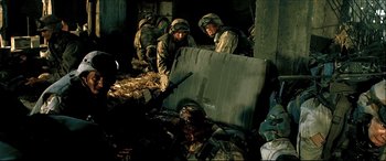 Movie still from “Black Hawk Down” (2001), directed by Ridley Scott – A group of men in fatigues standing next to a pile of trash; Medium shot, High angle
