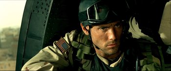 Movie still from “Black Hawk Down” (2001), directed by Ridley Scott – A man in a military uniform with an american flag patch on his hat; Close Up shot, Over the shoulder angle