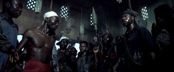 Movie still from “Black Hawk Down” (2001), directed by Ridley Scott – A group of men standing next to each other holding weapons; Medium shot, Low angle