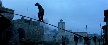 Movie still from “Black Hawk Down” (2001), directed by Ridley Scott – A skateboarder is doing a trick on a rail; Wide shot, Low angle
