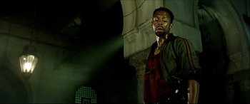 Movie still from “Black Hawk Down” (2001), directed by Ridley Scott – A man standing in front of a building with lights on; Medium shot, Low angle